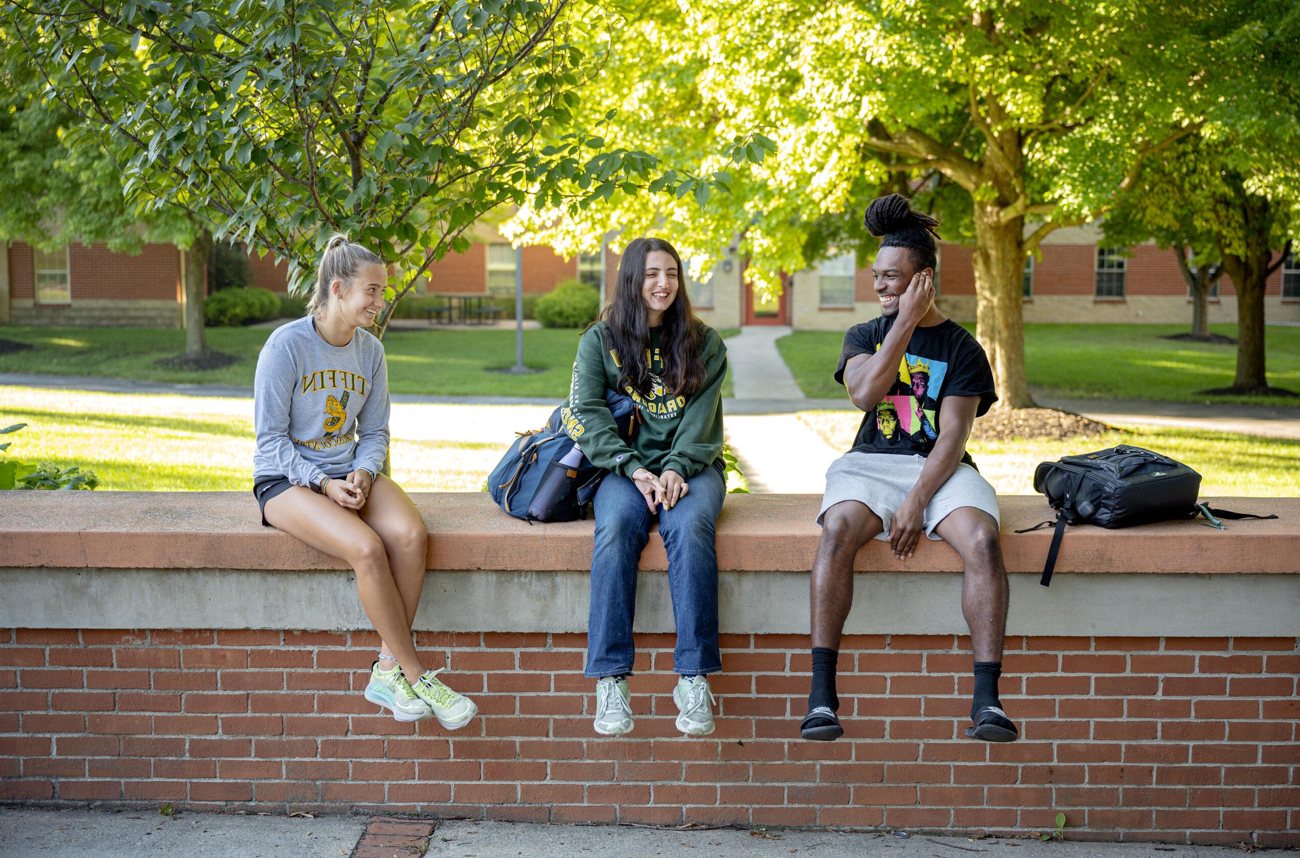three students smiling and talking outside